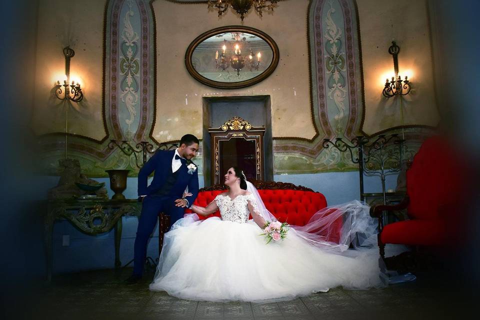 Novia sentada y novio parado en una sala