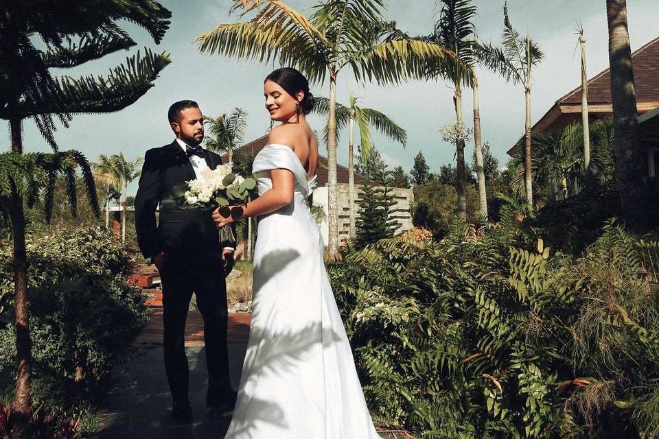 Novios posando en medio de un jardín con palmeras