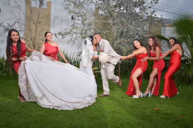 Pareja besándose mientras las damas de honor los jalan