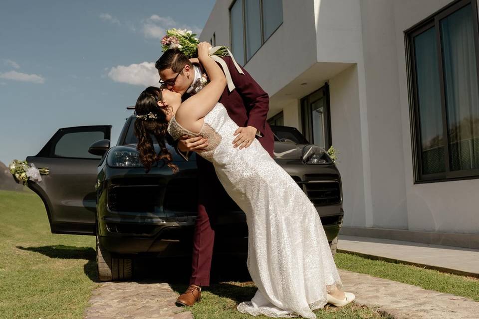 Novios besándose frente al auto