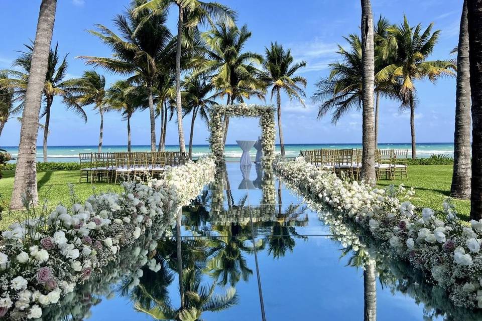 Pasillo al altar decorado con flores en un jardín frente a la playa