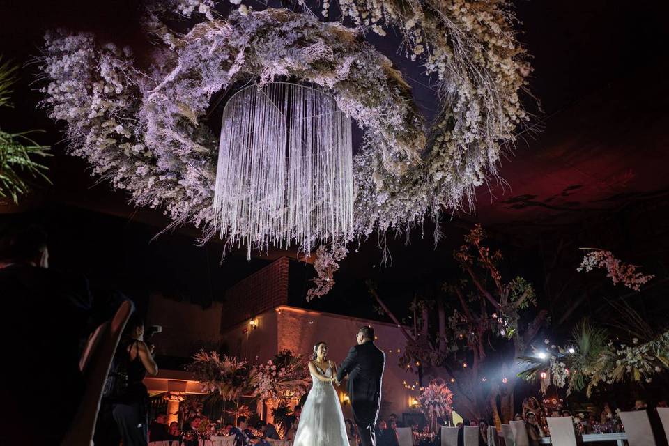 Novios bailando bajo un techo de flores