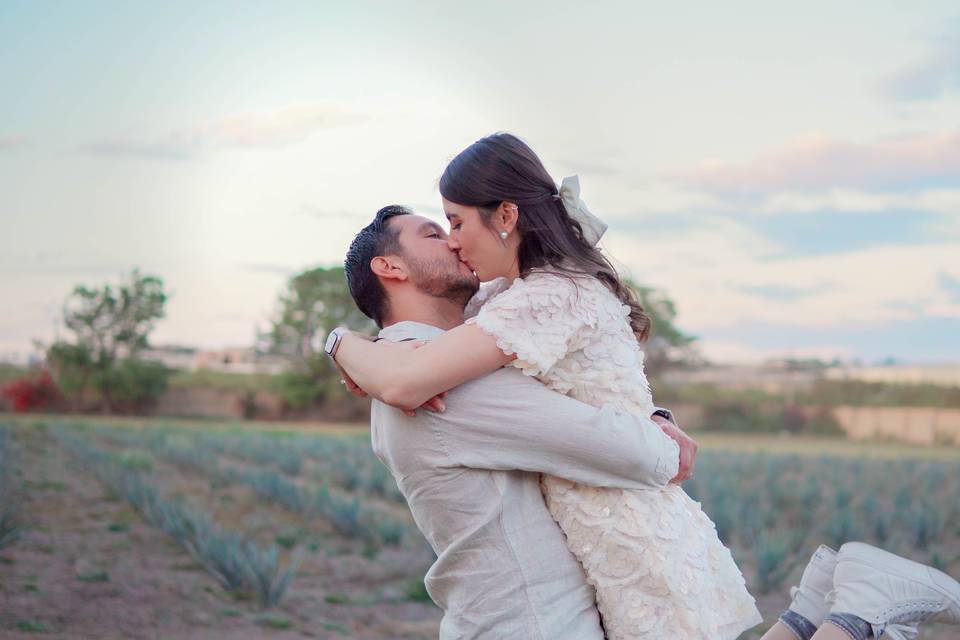 Pareja besándose en medio de un campo de agave