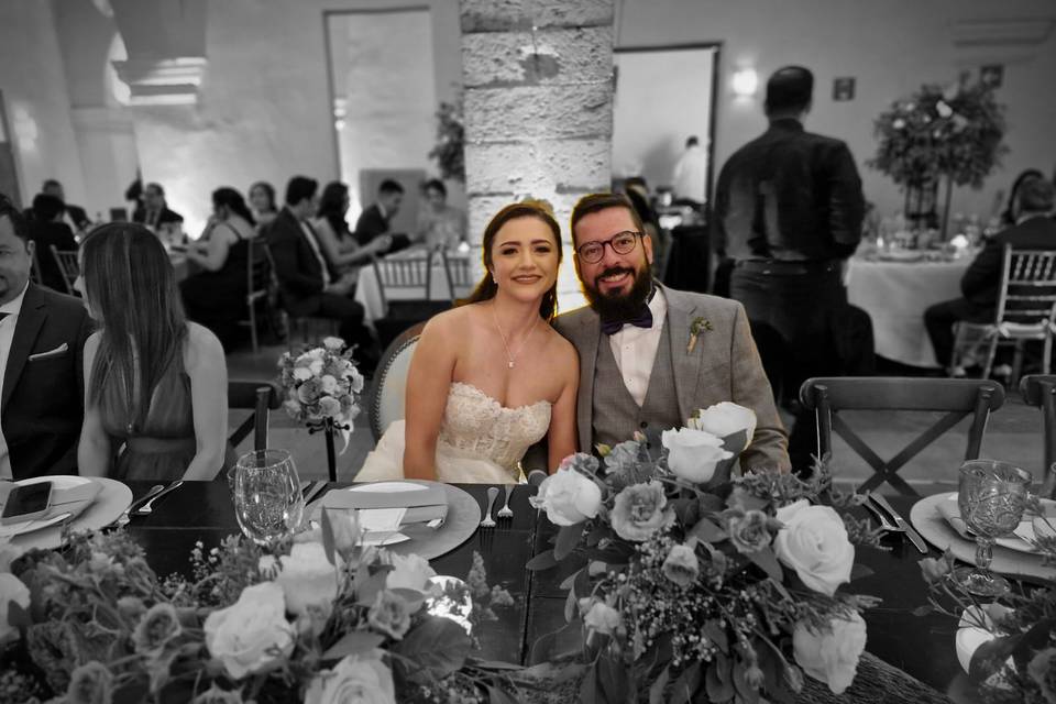 Novios sentados en una mesa con flores