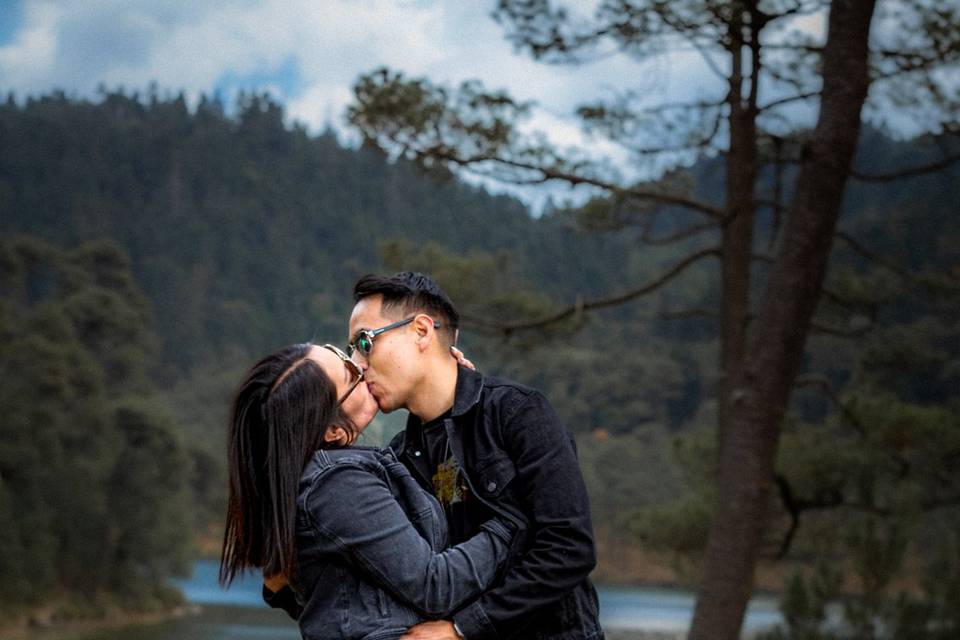 Pareja besándose frente a un lago con su perrito