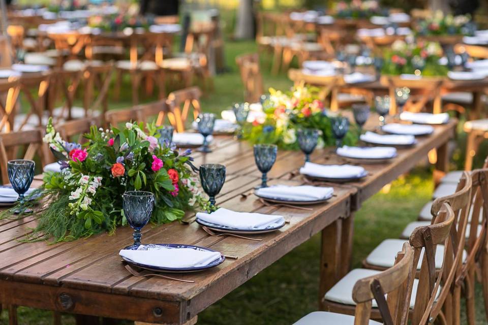 Mesa decorada con copas azules y arreglos florales