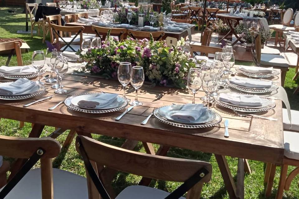 Mesa de madera con arreglo floral y vajilla