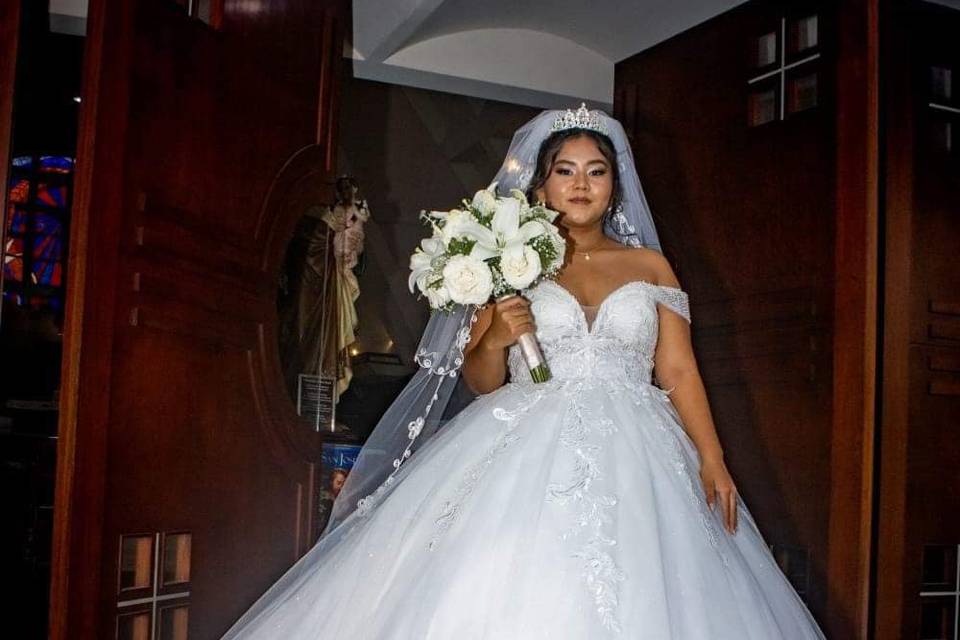 Novia con vestido corte princesa con velo y ramo de flores blancas