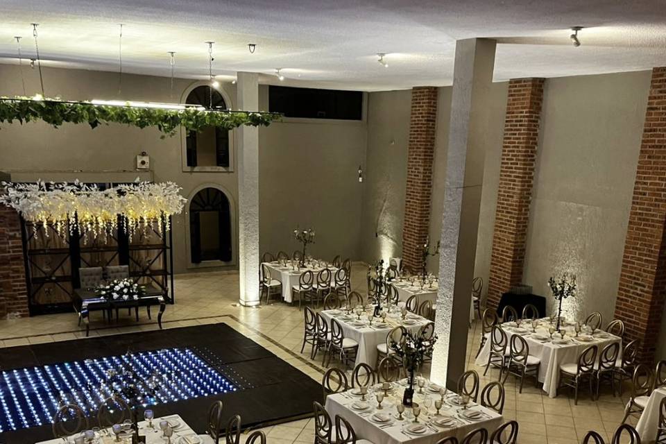 Evento con sillas y mesas beige y una pista de baile