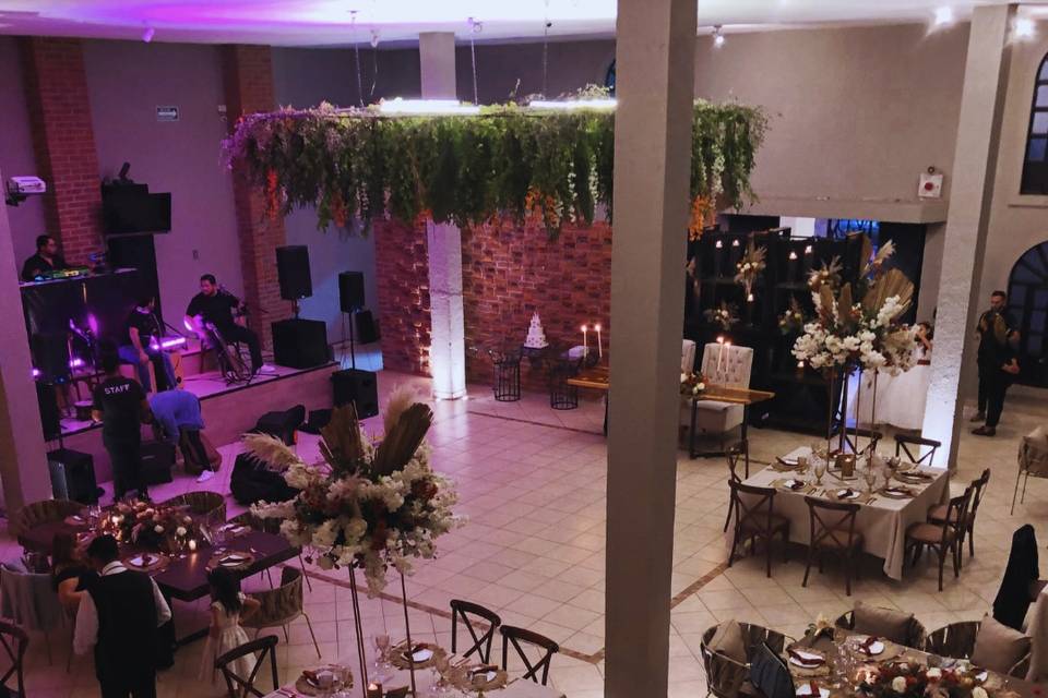 Salón con mesas cuadradas montadas con arreglos florales altos