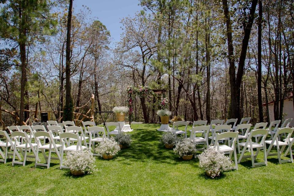 Sillas blancas para ceremonia en el jardín