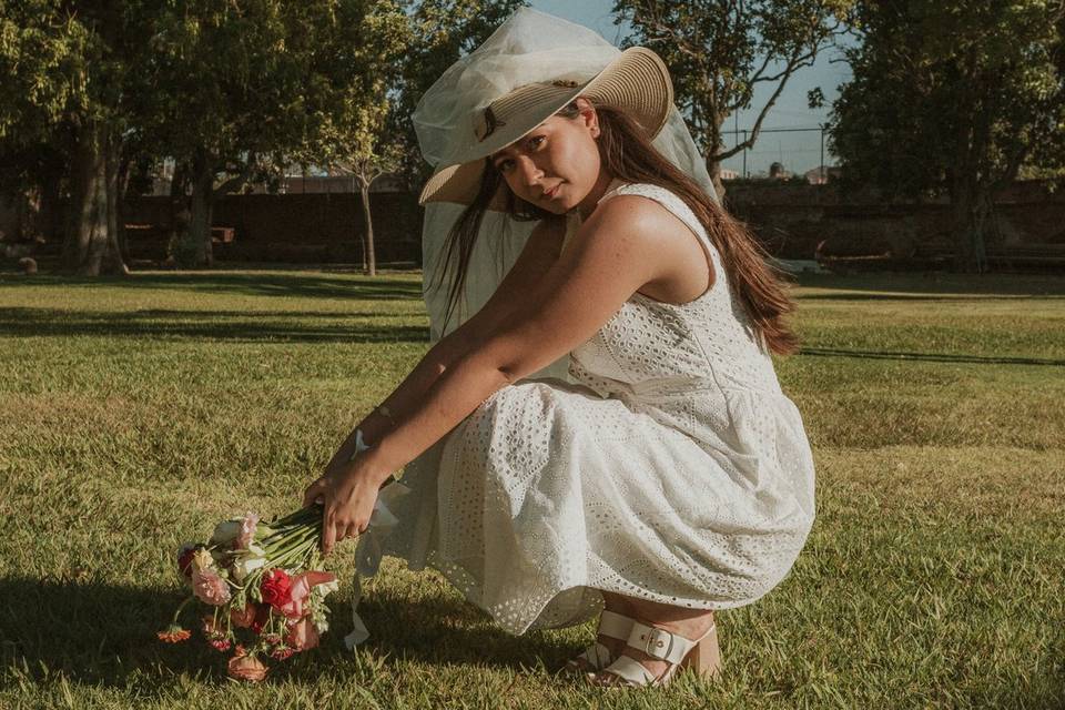 Novia posando en cunclillas en un jardín