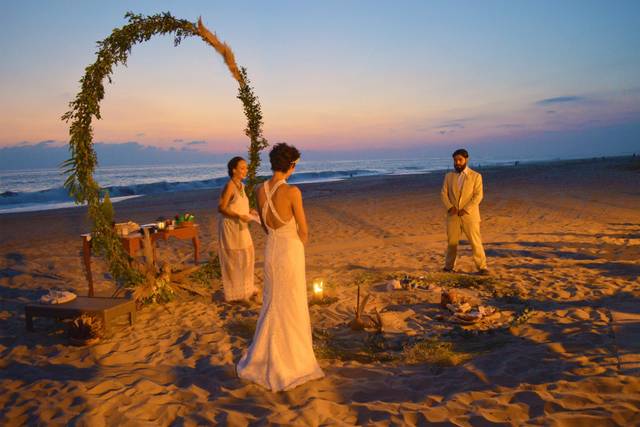 Novios en la arena casándose al atardecer