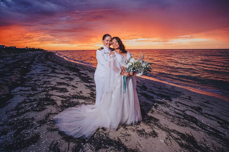 Novias abrazadas en la playa al atardecer