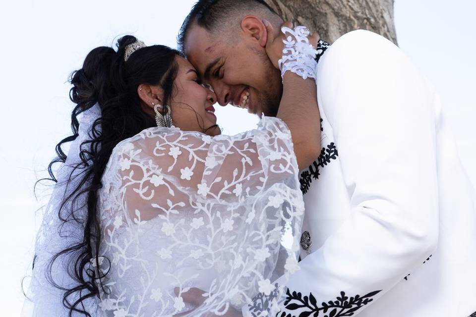 Novios sonriendo bajo un árbol