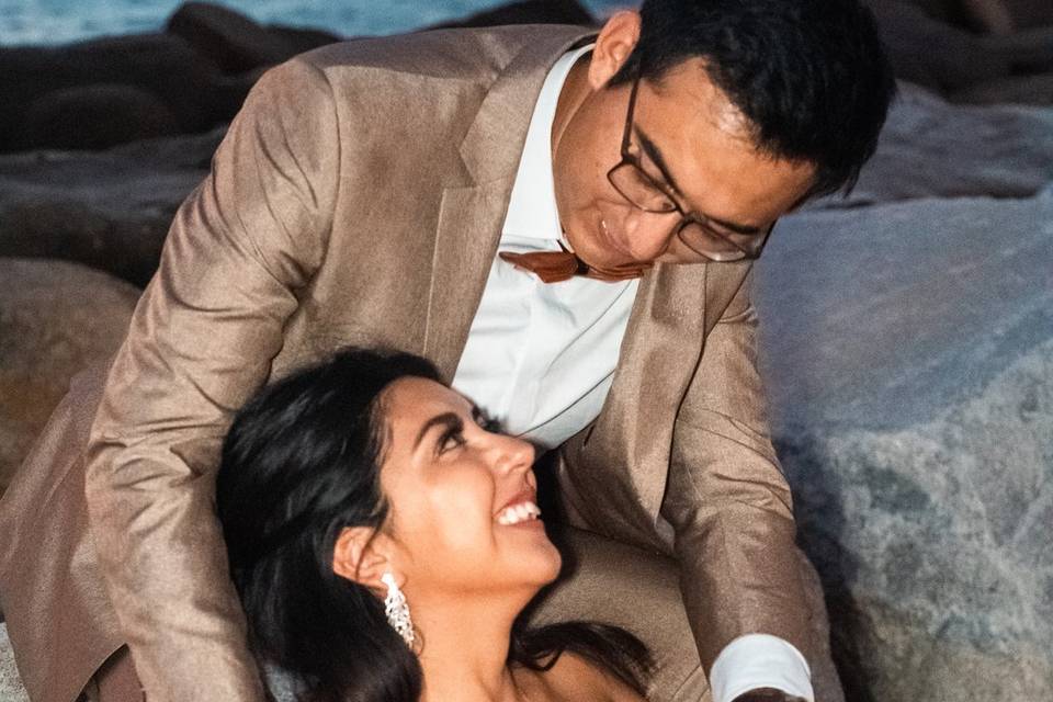 Novios sentados en las rocas frente al mar