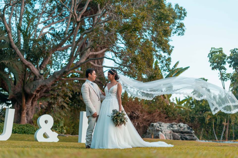 Novios en el jardín delante de letras gigantes blancas