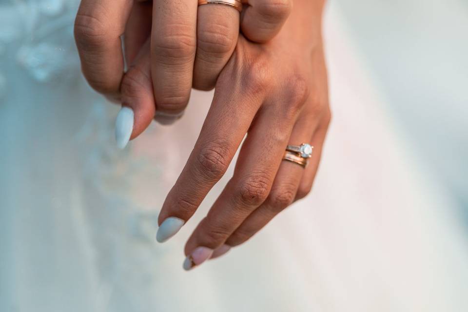 Manos entrelazadas con los anillos de matrimonio