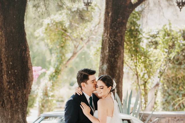 Novios posando en un auto blanco