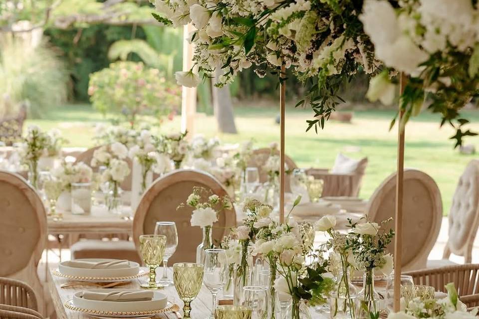Mea con copas verdes y arreglos florales altos