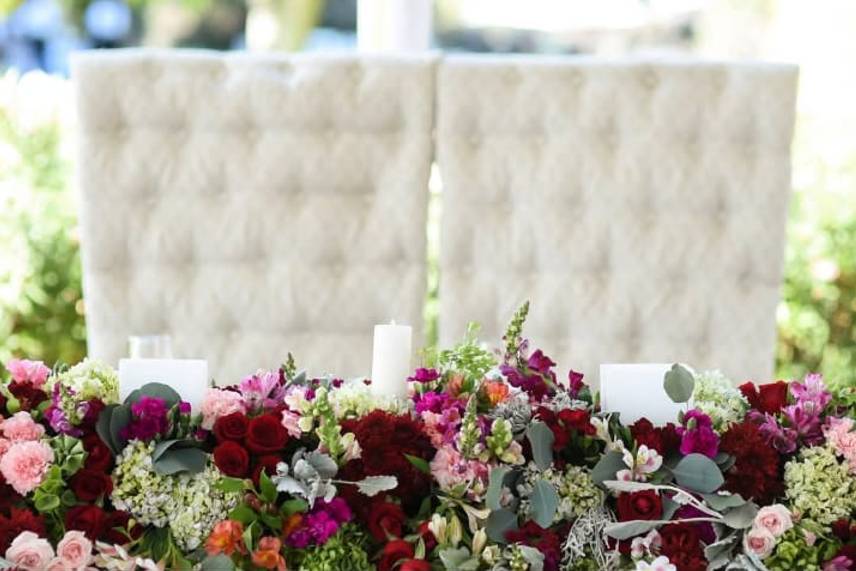 Sillas blancas de mesa de novios con arreglo floral
