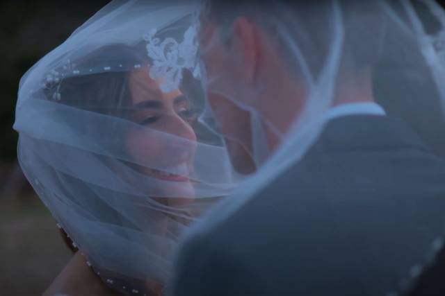 Novios sonriendo bajo el velo