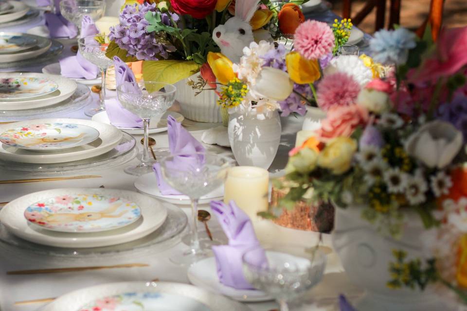 Mesa montada con platos blancos con arreglos florales de colores