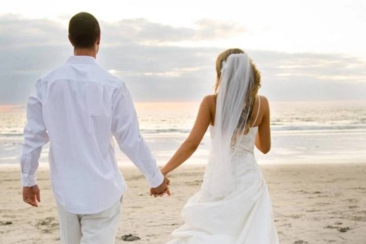 Novios de la mano caminando por la playa