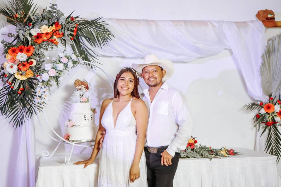 Novios posando con su pastel
